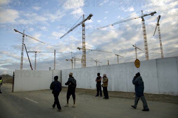 Workers arrive in the early morning to begin work on the new Greenpoint Stadium Seen from soccer fields in Greenpoint, construction cranes rise above the site of the new Greenpoint Stadium in Greenpoint, Cape Town. The all-weather stadium is designed to seat 70,000 people. The Stadium is one of 10 that will be used in the 2010 FIFA World Cup‚Ñ¢ / 2010 Soccer World Cup