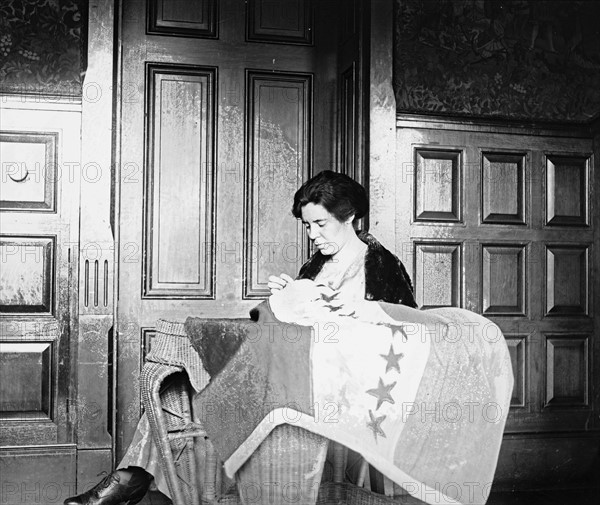 Portrait of Alice Paul, sewing suffrage flag.