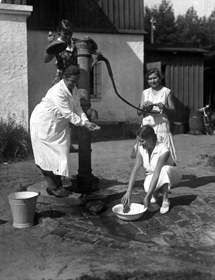 Three women fetching water from a pump