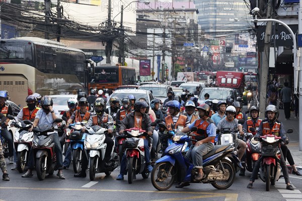 Many moped drivers are waiting at an intersection