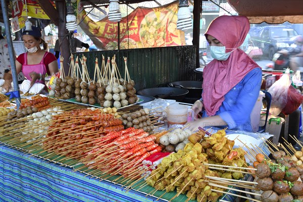 Saleswoman at the market stand with different skewers with meat and seafood