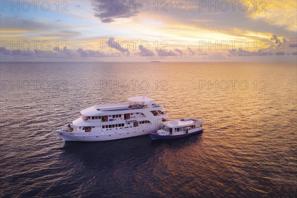 Diving safari ship MS Keana with diving dhoni anchored at sunset