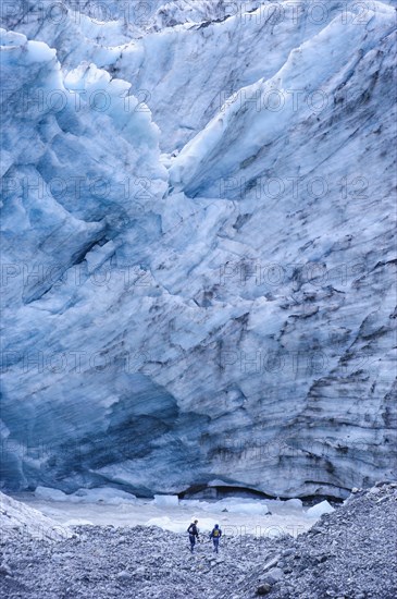 Tourist hiking to the giant glacial outflow of Fox Glacier