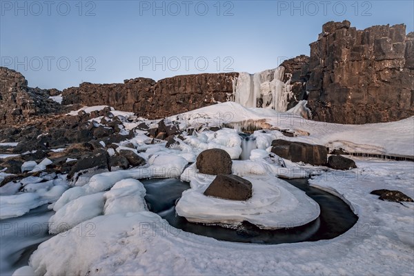 Partially frozen waterfall Oxararfoss in winter