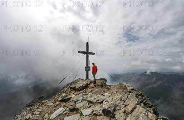 Hiker at the summit cross of Hochgolling