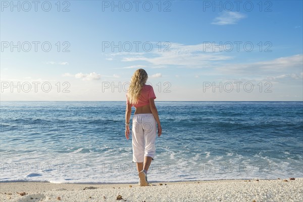 Young woman goes to the surf on a sandy beach