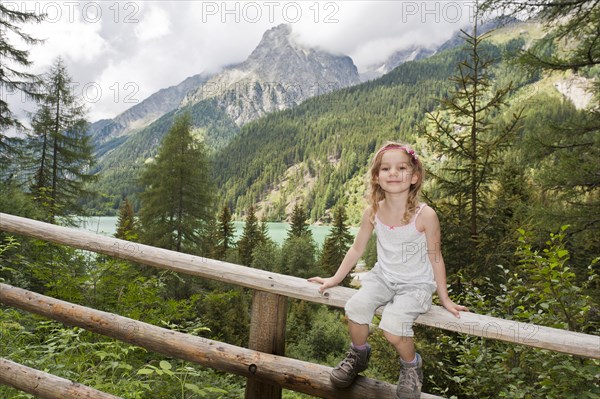 Little girl sitting on wooden railings