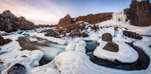 Partially frozen waterfall Oxararfoss in winter