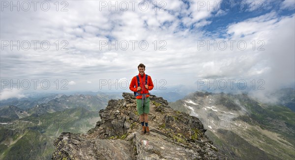 Hiker on the summit of the Hochgolling with rising fog