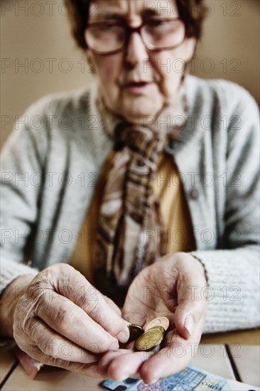 Senior citizen sits at the table and counts her money