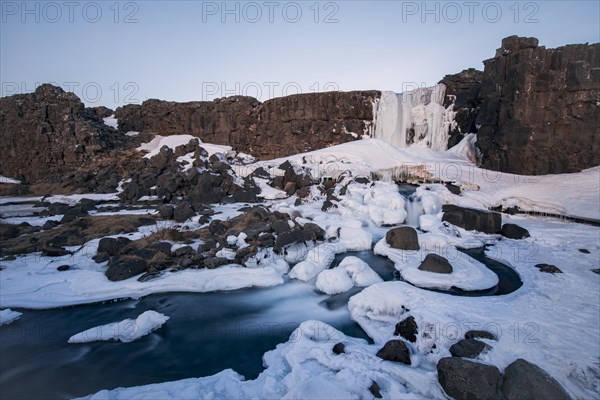 Partially frozen waterfall Oxararfoss in winter