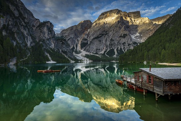 Green mountain lake with boats and boathouse