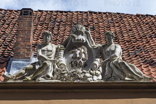 Art Nouveau figures on a roof with initials of the builder
