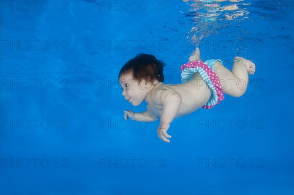 4 months infant learning to swim underwater in a pool