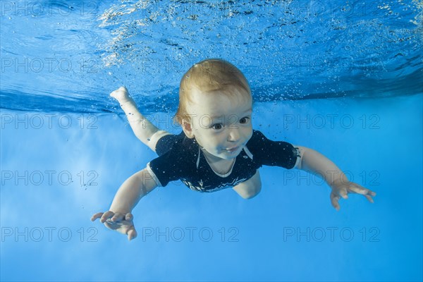 Little boy dives underwater in swimming pool