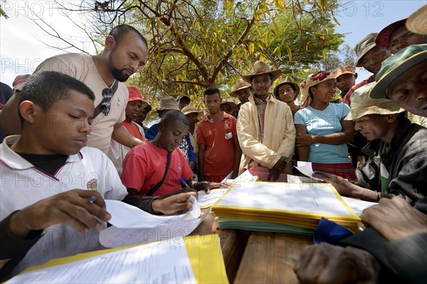 Villagers fill out applications for certification of their land on the village square