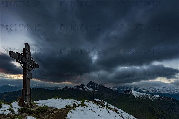 Cross on the summit of Zafernhorn with dark clouds