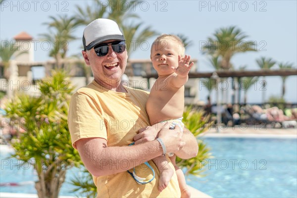 Happy father holding his cheerful son on holiday