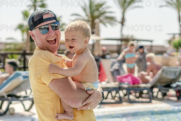 Happy father holding his cheerful son on holiday