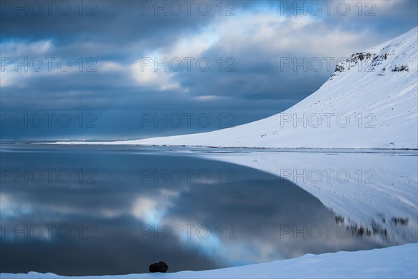 Snow-covered coastal landscape with water reflection