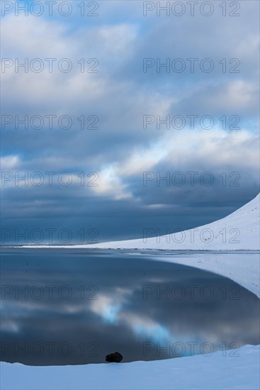 Snow-covered coastal landscape with water reflection