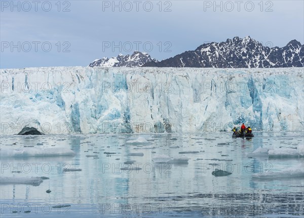 Zodiac boat with tourists navigating in front of Lilliehook glacier