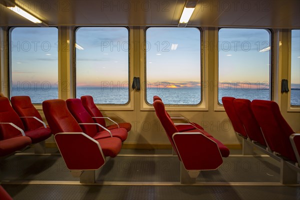 Red benches of a car ferry across the Gironde at sunset