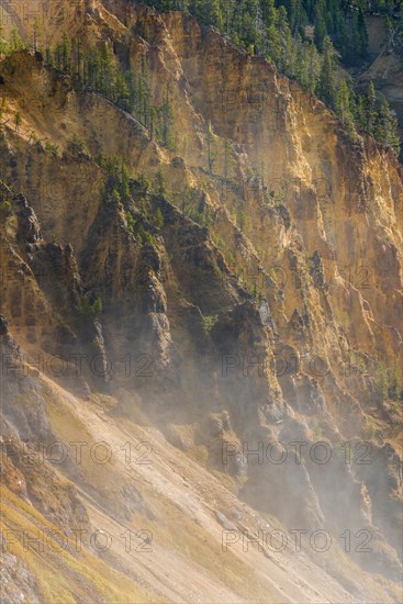 Rugged rock face of the Grand Canyon of the Yellowstone with water vapor of the waterfall