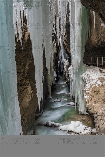 Path to Partnach wild river in the Partnach gorge with long icicles and snow in winter