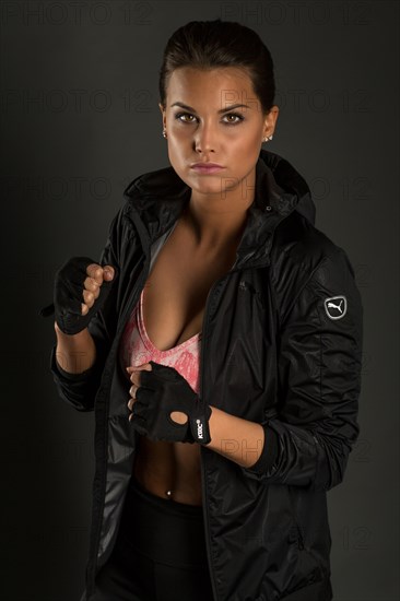 Portrait of a young woman with dark hair tied together in a sporty outfit