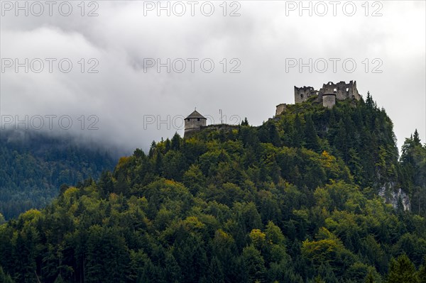 Castle ruin Ehrenberg with deciduous forest and mountains in the fog