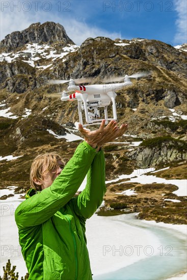 Young man catches a drone in the mountains