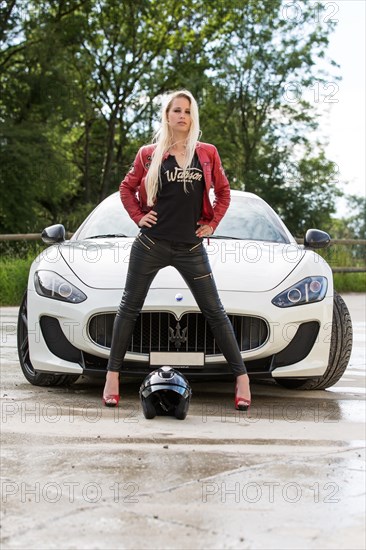 Young woman with long blond hair poses with white Maserati Gran Turismo MC Stradale