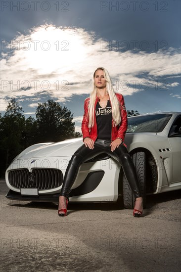 Young woman with long blond hair poses with white Maserati Gran Turismo MC Stradale