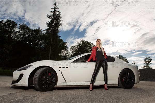 Young woman with long blond hair poses with white Maserati Gran Turismo MC Stradale