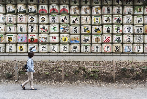 Woman walks pass sake barrels at Meiji Jingu Shrine