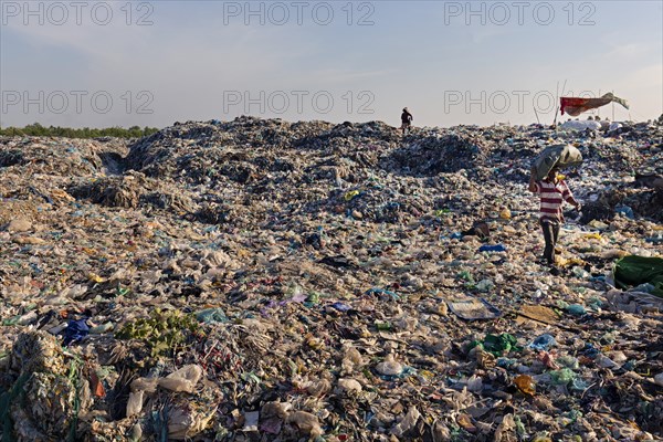 Garbage collector in garbage dump with plastic garbage