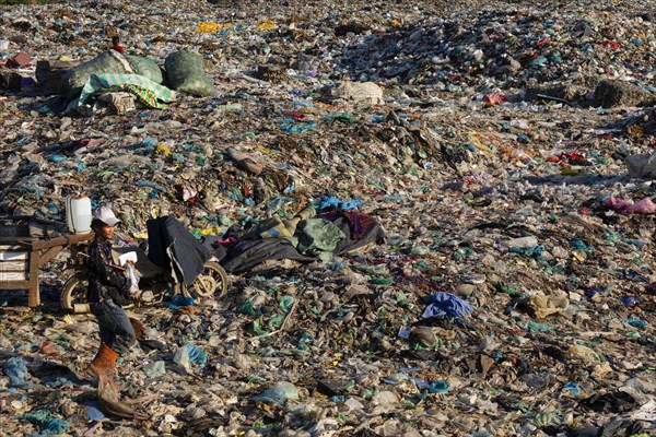 Garbage collector in garbage dump with plastic garbage