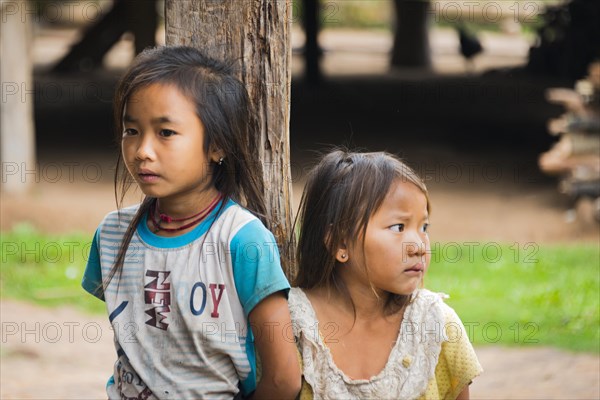 Two shy girls by a post of a hut