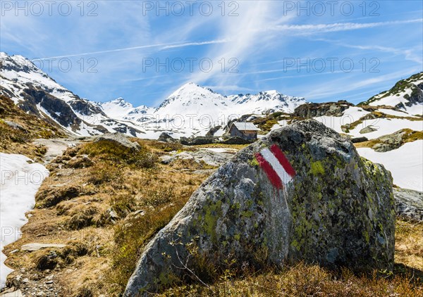 Red and white sign painted on rock marking hiking trail