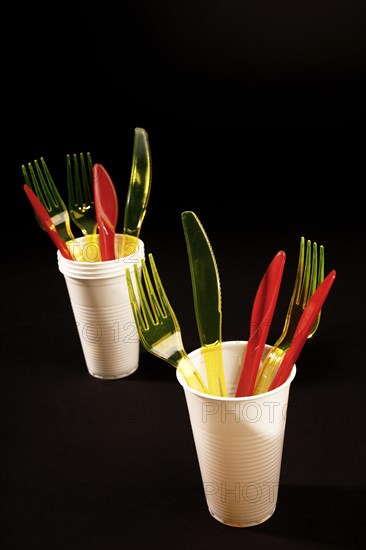 Red and yellow plastic cutlery in white plastic cups