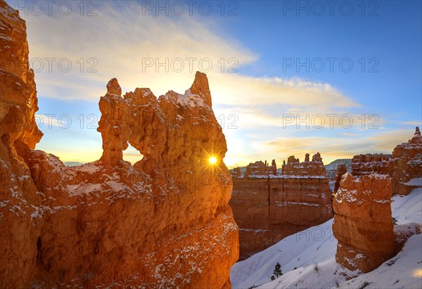 Sun star shining through hole in bizarre rock formation in morning light