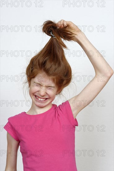 Girl with long red hair pulling her hair tie