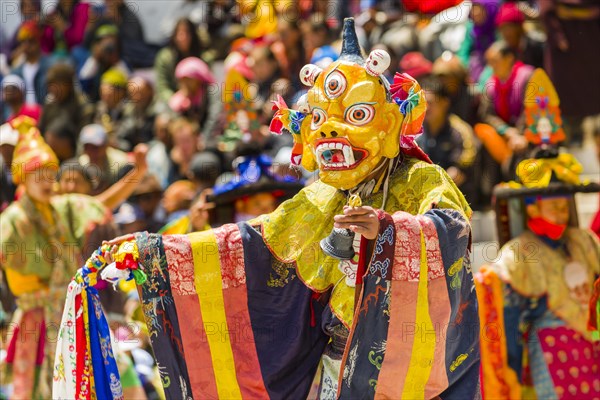 Monks with big wooden masks and colorful costumes are performing ritual dances at Hemis Festival in the courtyard of the monastery