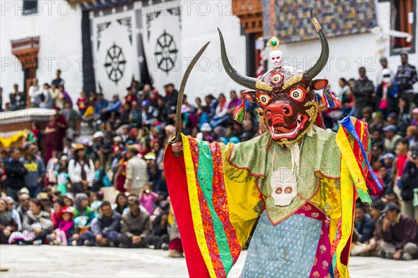 Monks with big wooden masks and colorful costumes are performing ritual dances at Hemis Festival in the courtyard of the monastery