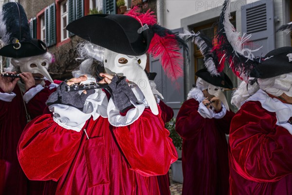 Many different groups of masked people walking through the streets of Basel