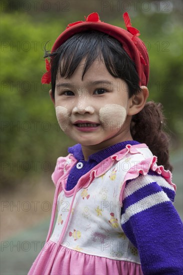 Local girl with a red cap and Thanaka paste on her face