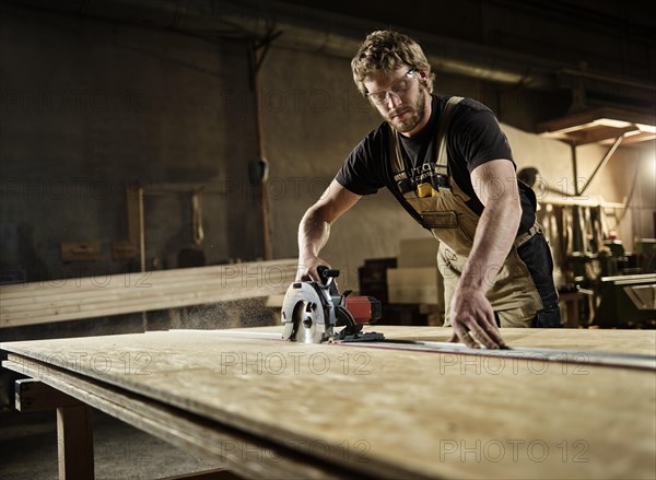 Carpenter cutting chipboard with a circular saw