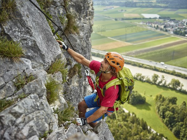 Climber with orange helmet climbing the via ferrata