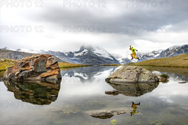 Hiker jumps on rocks in the lake